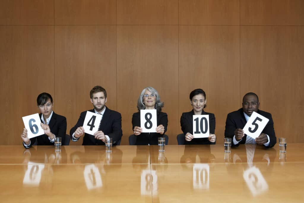 Executives at conference table holding score cards, portrait