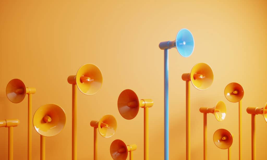 Blue colored megaphone standing out from the crowd